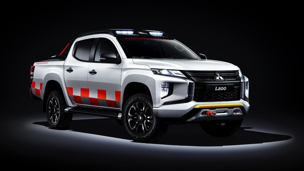 Wallpaper da picape Mitsubishi L200 Branca em versão Mountain Rescue, com luzes de teto e detalhes em vermelho, em fundo de estúdio