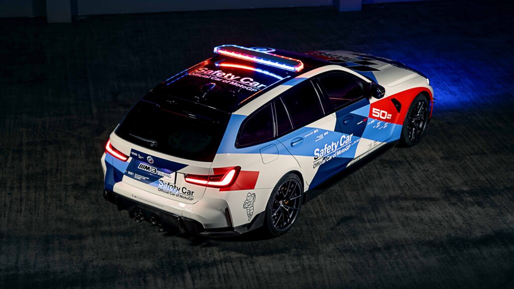 Papel de parede da perua BMW M3 Touring (G81) como Safety Car oficial do MotoGP, com pintura M Motorsport comemorativa de 50 anos, vista de trás com giroflex.