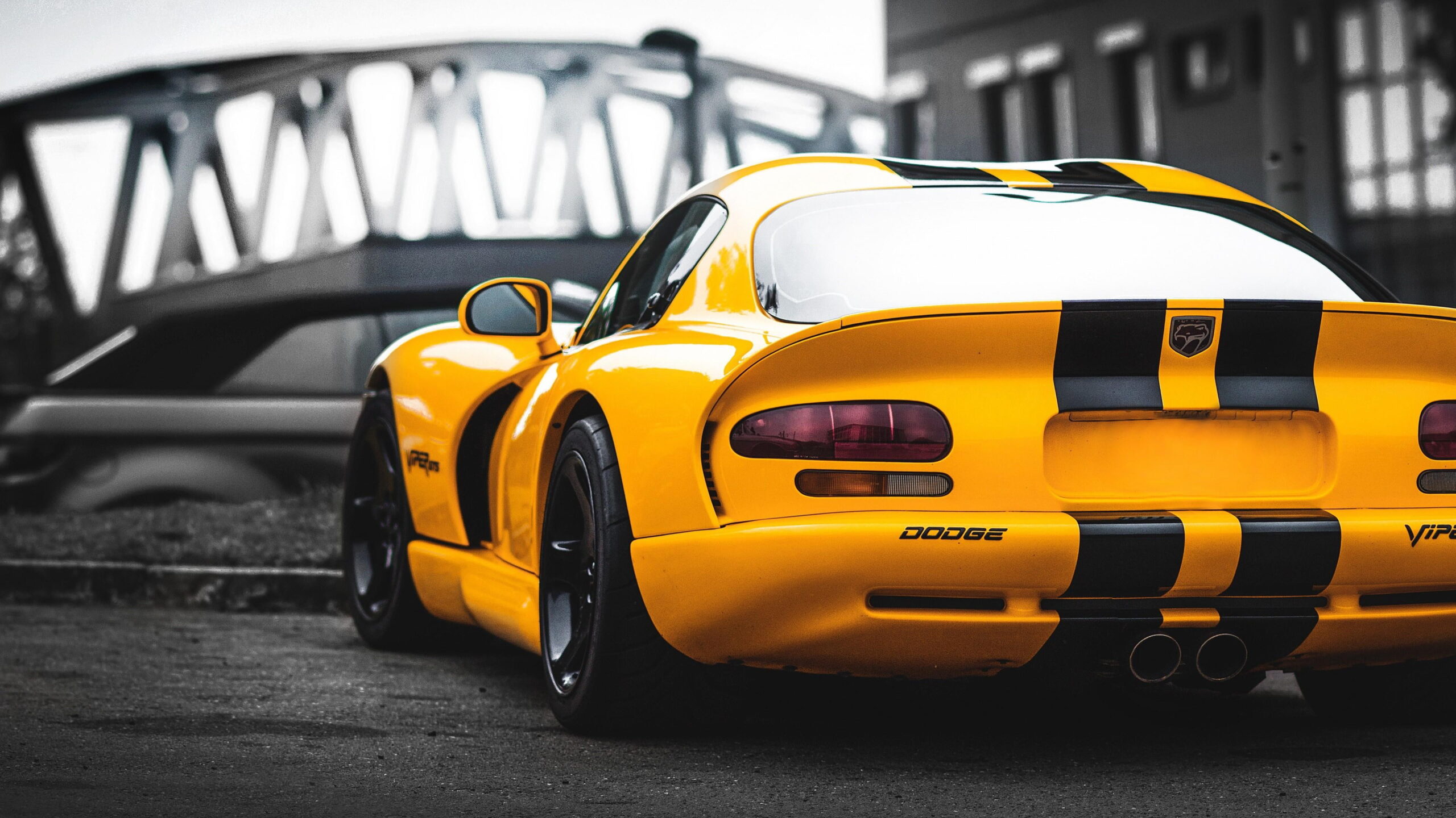 Dodge Viper GTS Amarelo Papel de parede de um Dodge Viper GTS amarelo com listras pretas, visto de trás, com um fundo industrial/ponte desfocado.