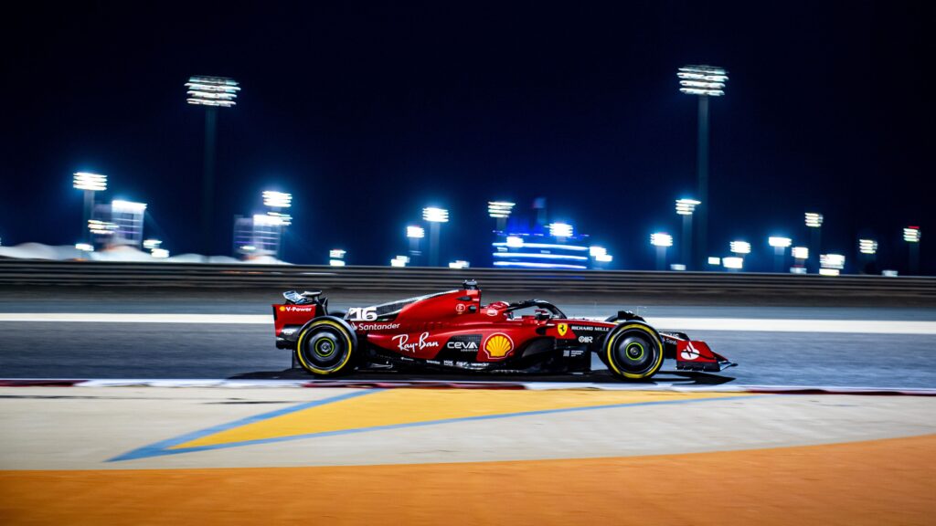 Papel de parede do carro de Fórmula 1 Ferrari SF-23, número 16 (Charles Leclerc), correndo em alta velocidade no circuito do Bahrain à noite, com os refletores ao fundo.