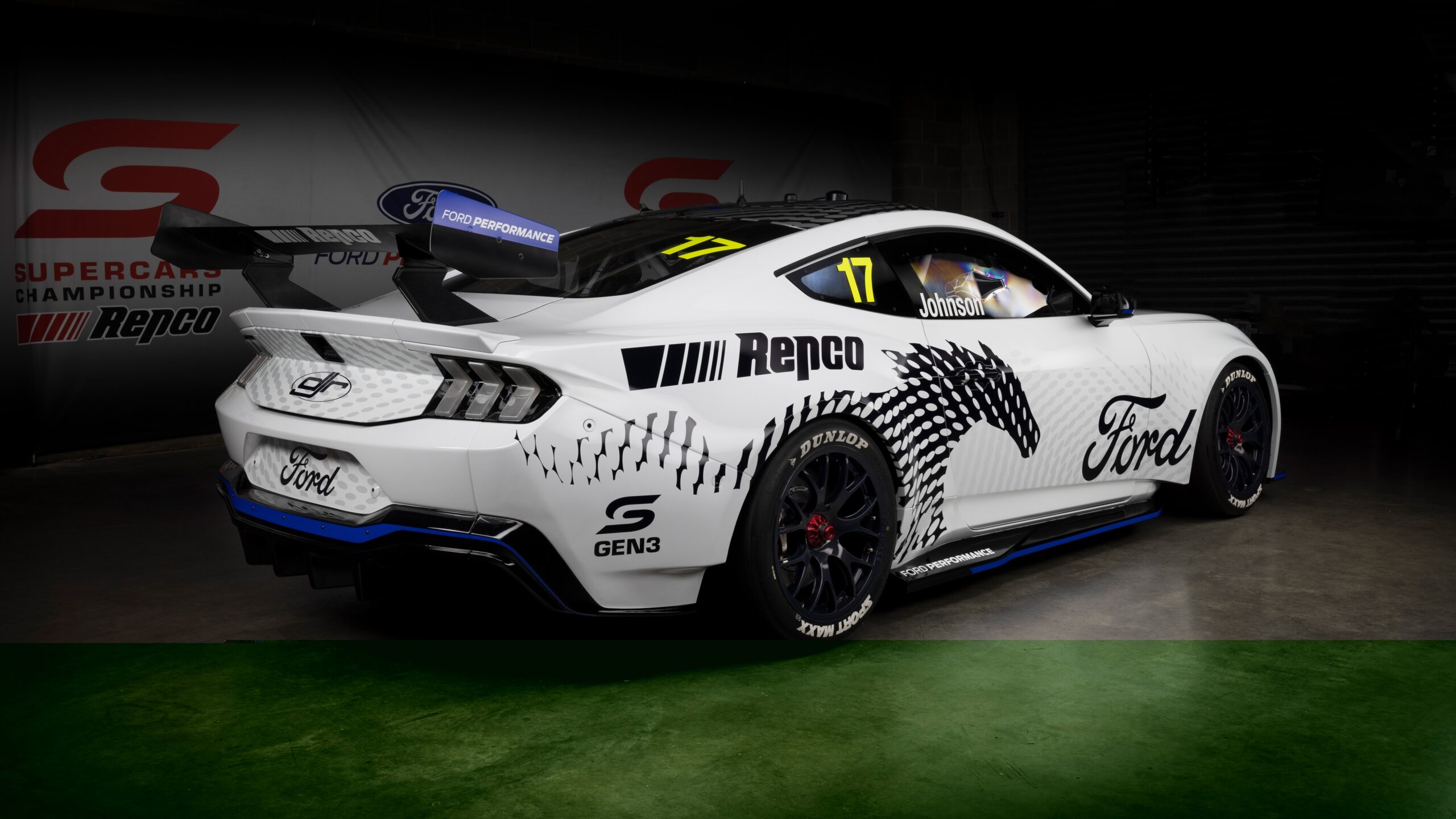 Ford Mustang Gen3 Supercar Papel de parede do carro de corrida Ford Mustang Gen3 Supercar da equipe DJR (Dick Johnson Racing), com pintura branca e azul, visto de frente em estúdio.