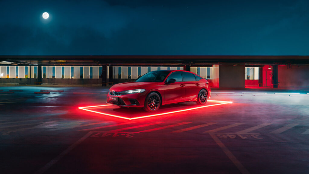 Papel de parede do novo Honda Civic sedan (Geração 11) vermelho, estacionado em um terraço à noite, com uma luz de neon vermelha no chão e a lua ao fundo.