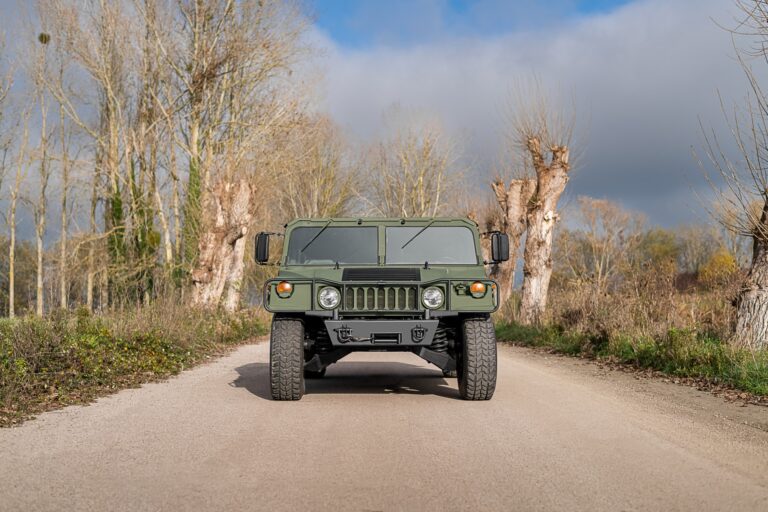 Papel de parede frontal de um AM General Hummer H1 (Humvee) na cor verde militar, em uma estrada de terra estreita em um dia claro.