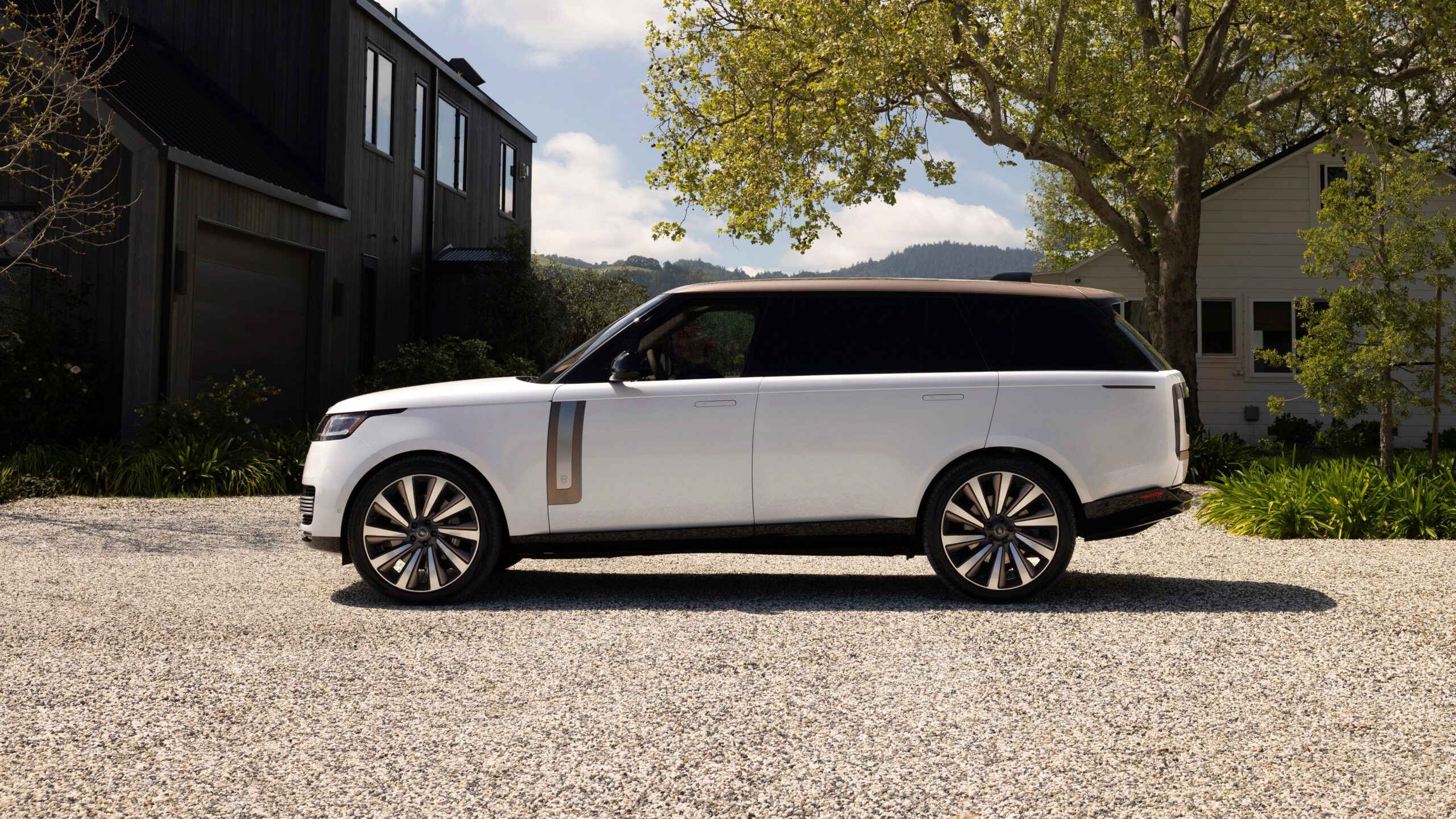 Range Rover SV Papel de parede do perfil de um SUV de luxo Range Rover SV (L460) branco, com teto e detalhes em bronze, estacionado em uma entrada de cascalho.