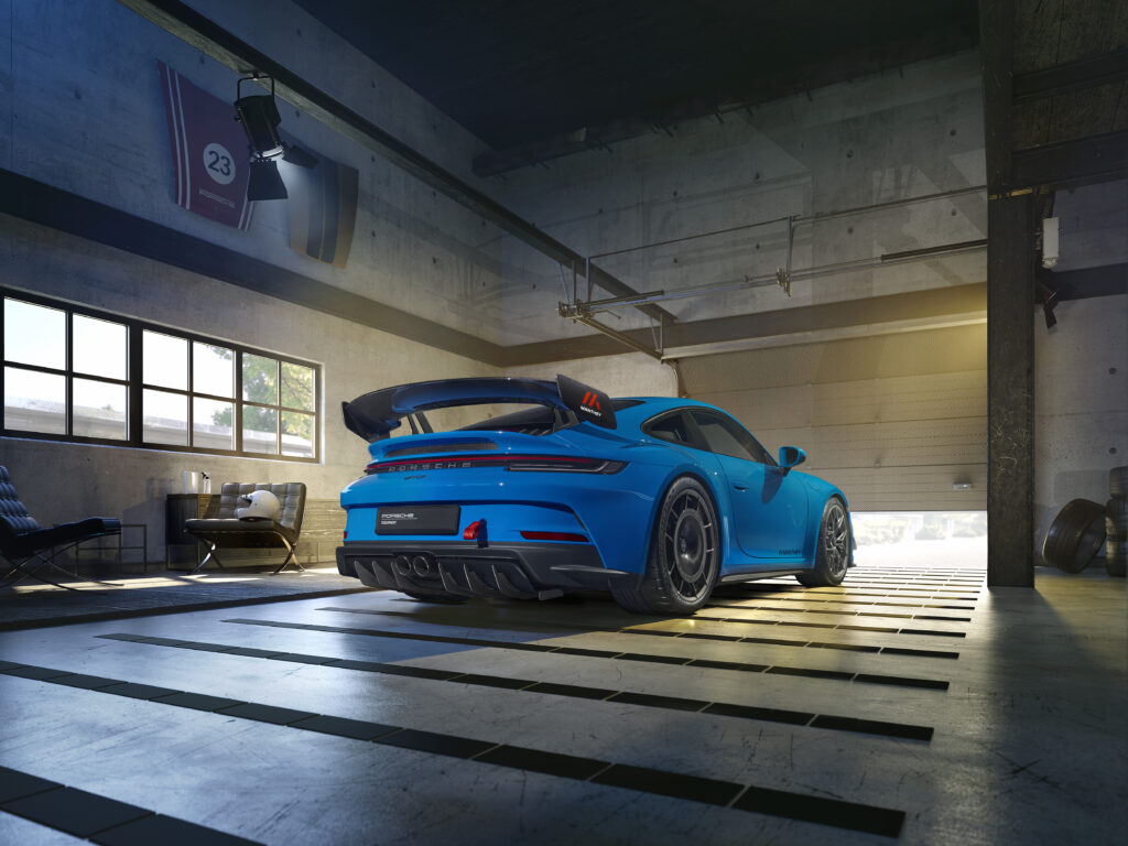 Fundo de tela da traseira de um Porsche 911 GT3 RS (geração 992) na cor Azul (Shark Blue), destacando o aerofólio "swan neck" com DRS, em uma garagem moderna.